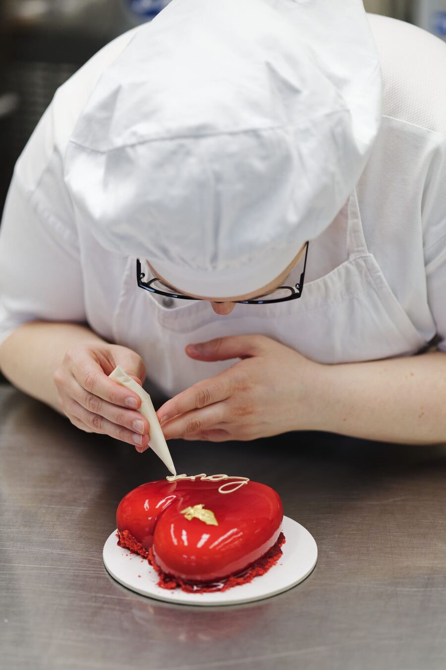 Una pasticcera rifinisce un dolce a cuore rosso