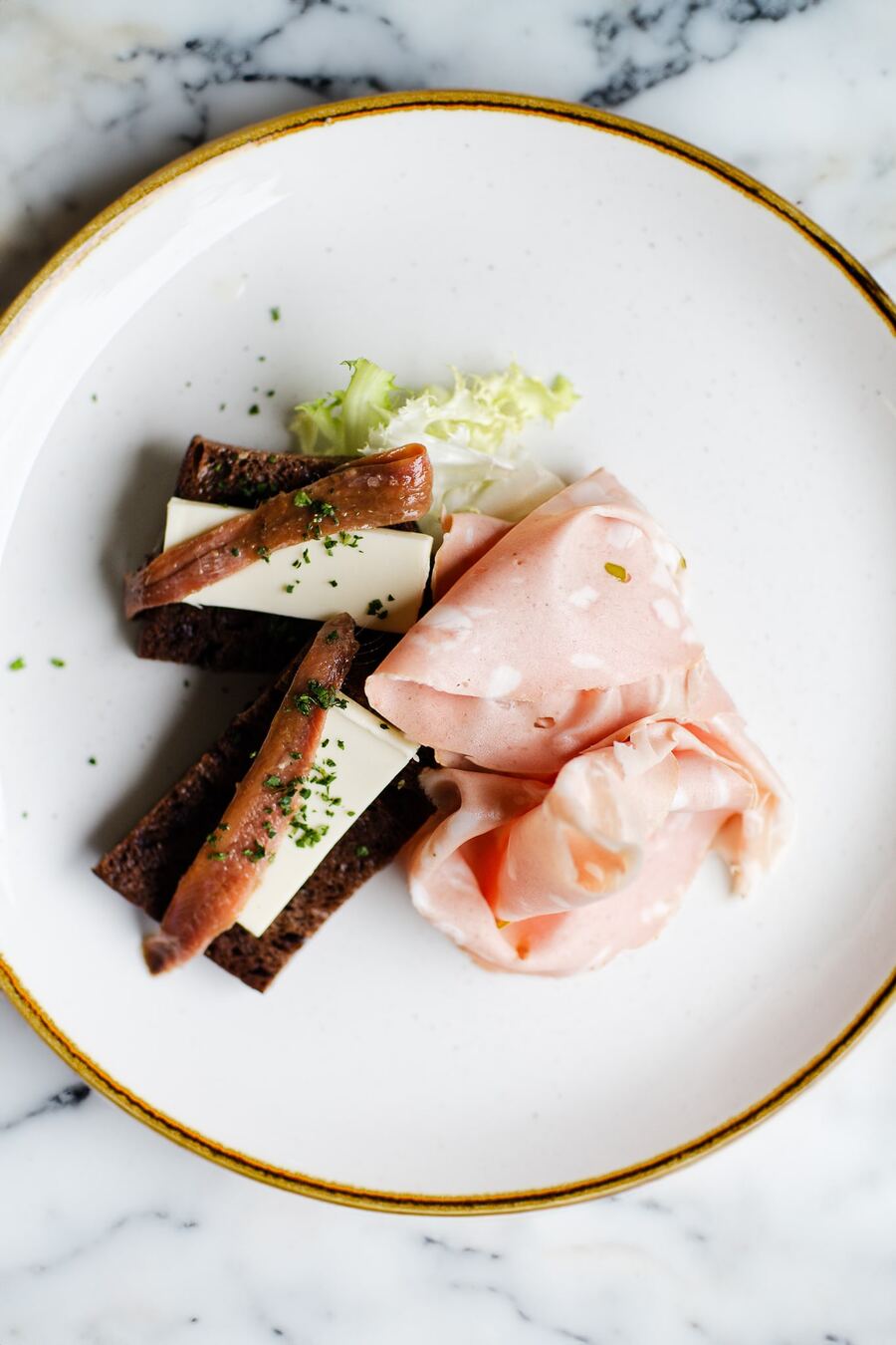 Un piatto con affettati e formaggio su marmo